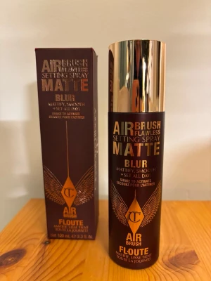 Charlotte Tilbury Airbrush Setting Spray - Airbrush Flawless Setting Spray Matte Blur från Charlotte Tilbury. Brun cylinderformad flaska med guldfärgat lock och detaljer i guld. Ger en matt, slät finish och håller sminket på plats hela dagen. Innehåller 100 ml.