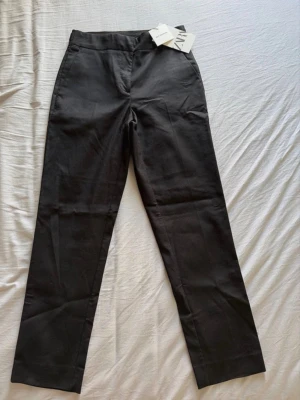 Svarta kostymbyxor från Zara - Snygga svarta kostymbyxor från Zara med raka ben och hög midja. Byxorna har diskreta fickor bak och är tillverkade i ett slätt tyg som ger en clean look. Perfekta för dig som gillar stilrena och klassiska plagg.