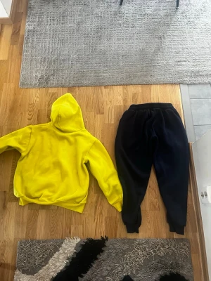 Svart gul  YES BOSS dress - Säljer ett par svarta mjukisbyxor från YES BOSS och en gul tröja.  vit text på ena benet. Byxorna har resår i midjan och muddar vid bensluten för en skön och avslappnad passform. Perfekta för chill dagar eller när du vill vara bekväm.