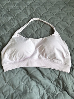 Ljuslila sömlös bh från MYMNT - Ljuslila bh från MYMNT i mjukt, stretchigt material. Modellen är sömlös med bred resår under bysten och brottarrygg för extra stöd och komfort. Diskret MYMNT-logga bak på resåren. Perfekt för dig som vill ha en enkel och bekväm bh i sportig stil.