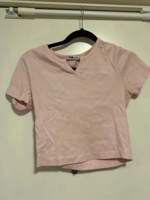 Ljusrosa croppad t-shirt - Söt ljusrosa croppad t-shirt från New Yorker med korta ärmar och en liten v-ringning vid halsen. Perfekt till jeans eller kjol för en avslappnad och trendig look.