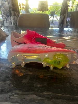 Nike Mercurial superfly 11 fotbollsskor rosa  - (har tyvvär tappat bort min box) helt oanvända och perfekt kondition och kan diskutera om prisen. Säljer ett par Nike Mercurial Vapor fotbollsskor i en snygg rosa färg med svarta detaljer. Skorna har en lätt ovandel i syntetmaterial och genomskinlig sula med neonfärgade inslag och fasta dobbar för gräsplan. Perfekta för dig som vill ha speed och kontroll på planen.