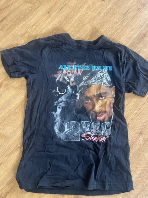 Svart 2Pac All Eyez On Me t-shirt - Säljer en svart t-shirt med tryck av 2Pac och texten 'ALL EYEZ ON ME' framtill. Använt några gånger och har nu bara legat.