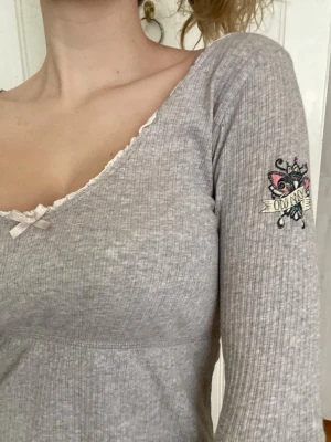 Ljusgrå ribbad topp med spetsdetalj Odd Molly - Supersöt ljusgrå ribbad topp med lång ärm, liten rosett och spetskant vid ringningen. Litet hål se sista bild💕 Odd Molly