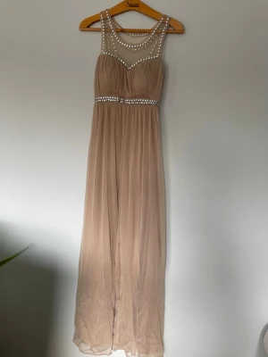 Beige festklänning  - Använd en gång. Inga fläckar och inget slitage. Sista bilden visar färgen bäst. Längd: ca 156 cm Byst: ca 38cm Midja: ca 32cm