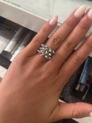 Edblad ring - Cool ring i silverfärgad metall med flera små pyramidformade nitar på ovansidan. Ringen har en bred design som ger ett edgy och trendigt intryck. Perfekt för dig som gillar statement-smycken och vill sticka ut.