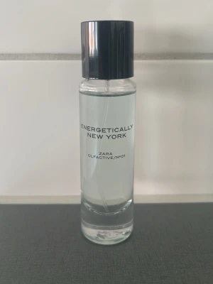 Energetically New York parfym Zara - Energetically New York från Zara är en stilren parfym i en genomskinlig glasflaska med svart cylinderformat lock. Flaskan har minimalistisk text i svart och rymmer en fräsch doft som passar perfekt för dig som gillar moderna och urbana vibbar.