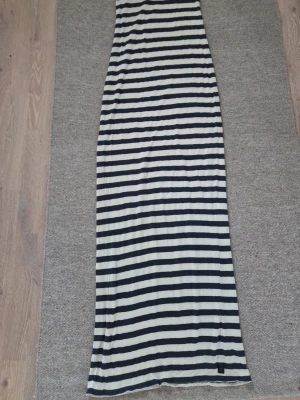Randig långklänning Tiger of Sweden - Säljer en lång, randig klänning från Tiger of Sweden Jeans i marinblått och vitt. Klänningen har raka linjer och är tillverkad i mjuk bomull, perfekt för en avslappnad och stilren look.