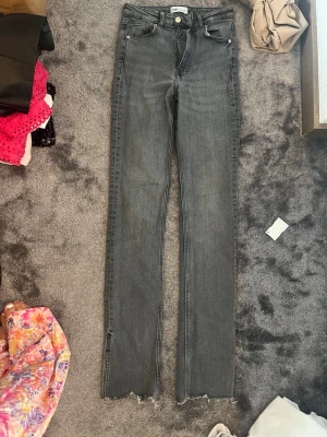 Grå raka jeans från ZARA - Säljer ett par grå jeans från ZARA med raka ben och råa kanter nertill. Jeansen har klassisk femficksmodell, bälteshällor och dragkedjegylf. Perfekta för en avslappnad och trendig look.