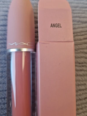 MAC Angel rosa läppstift - MAC Angel läppstift i en mjuk rosa nyans. Hylsan är stilren med matt rosa lock och silverdetalj, och kommer i matchande rosa förpackning. Klassisk MAC-design med genomskinlig botten som visar färgen. Perfekt för dig som gillar naturliga, fräscha läppar.