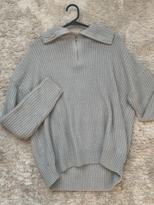 Grå stickad tjocktröja med halvzip - Mysig grå stickad tröja med halvzip och stor krage. Tjocktröjan är bekväm och väldigt fin på. Den är storlek S men oversized, så känns mer som M.
