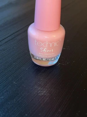 Technic Sheer ljusrosa nagellack - Säljer ett Technic Sheer nagellack i en mjuk ljusrosa nyans. Lacket kommer i en rund glasflaska med rosa kork och rymmer 12 ml. Perfekt för dig som gillar en naturlig och fräsch look på naglarna.