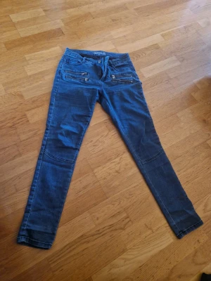 Blå skinny jeans med dragkedjor - Snygga blå skinny jeans från 30 Denim med flera coola dragkedjor framtill. Jeansen har en klassisk femficksmodell och smal passform som sitter tajt längs benen. Materialet är stretchigt denim för extra komfort och stil.