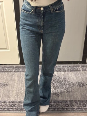 Blå bootcut jeans från ASOS DESIGN - Säljer ett par blå bootcut jeans från ASOS DESIGN i modellen Tall. Jeansen har hög midja, klassisk femficksdesign och är gjorda i ett mjukt denimtyg. Perfekta för dig som gillar en tidlös look med lite utsvängda ben.