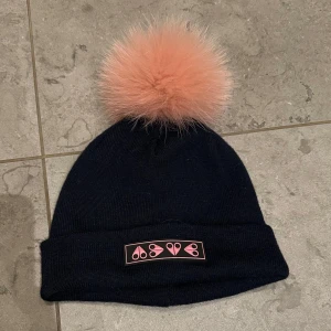 Svart mössa med rosa pälsboll - Snygg svart Moose Knuckles mössa med en stor rosa pälsboll på toppen. Passar perfekt till kalla dagar ❣️ Nyskick