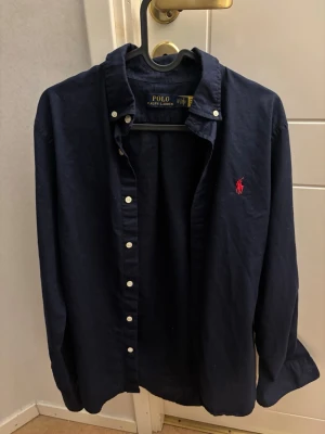 Mörkblå skjorta från Polo Ralph Lauren - Ralph Lauren-skjorta i nyskick, helt oanvänd. Storlek XS, men passar även dig som vanligtvis har storlek S. Klassisk modell och perfekt skick