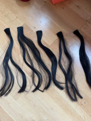 Svarta clip-on löshår - Säljer ett set svarta clip-on löshår. Löshåret är rakt och har flera delar för enkel applicering och styling. Perfekt för dig som vill ha längre eller fylligare hår på nolltid. Clipsen är diskreta och lätta att fästa.