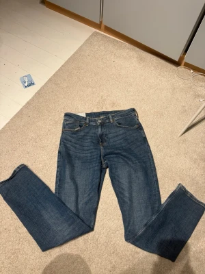 Blå raka jeans med fem fickor - Klassiska blå jeans i rak modell med fem fickor och normal midja. Jeansen har en tidlös tvätt och är tillverkade i denim med synliga sömmar. Passar perfekt till en avslappnad stil och är ett måste i garderoben. 32/32