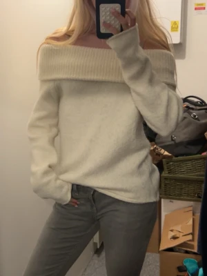 Off shoulder cremevit stickad tröja - Säljer en cremevit stickad tröja med bred off shoulder-krage. Tröjan har lång ärm och är gjord i ett mjukt, fluffigt material som känns riktigt cozy. Perfekt för dig som gillar en avslappnad men ändå trendig look.