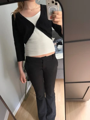 Svart croppad kofta med trekvartsärm - Svart croppad kofta med trekvartsärm och öppen framtill. Enkel och stilren design som passar över linne eller t-shirt. Mjukt och stretchigt material som gör den bekväm och lätt att bära. Perfekt för lager-på-lager-stil.