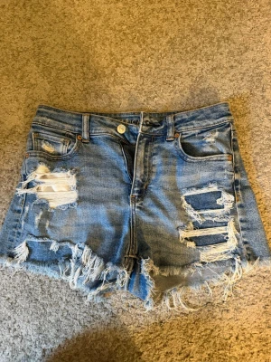 Blå slitna jeansshorts -  jeansshorts med slitna detaljer. Strech matrial och high waist, men om man viker ner de där uppe så är de jätte snygga.