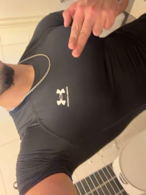 Svart tight träningströja Under Armour - Säljer en svart, tight och kortärmad träningströja från Under Armour. Tröjan har en rund halsringning och är tillverkad i ett stretchigt funktionsmaterial som andas. Perfekt för gymmet eller löpning.
