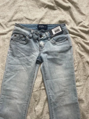 Ljusblå bootcut jeans från G rise - Snygga ljusblå jeans från g rise med bootcut modell. Jeansen har en tvättad look och är tillverkade i ett mjukt denimtyg som ger en avslappnad vibe. Perfekta för dig som gillar retrostil och vill ha ett par jeans som sticker ut. Modellen är I short och färgen ice