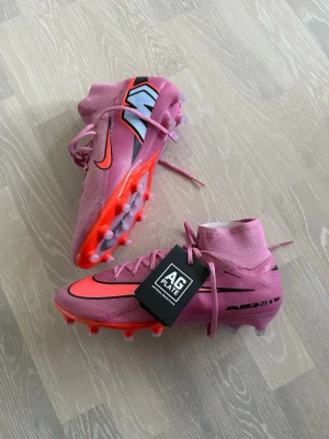  Nike fotbollsskor AG  - Snygga rosa fotbollsskor från Nike med högt skaft och AG Plate-dobbar för konstgräs. Helt nya storlek 44