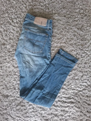 Ljusblå  Tiger of sweden slim fit jeans - Säljer ett par ljusblå slim fit jeans med klassisk femficksdesign och snygga slitningar framtill. Jeansen har normal midja och raka ben. Tillverkade i mjukt denimtyg som ger en skön känsla och passar perfekt till en avslappnad stil.