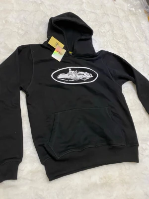 Svart hoodie och byxa set - Snyggt svart set med hoodie och byxa, båda med vit tryckt logga framtill. Hoodien har magficka och byxan har resår i midja och benslut. Perfekt för en avslappnad och trendig stil.