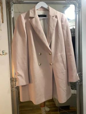 Ljusrosa kavaj klänning från Zara Basic - Stilren ljusrosa kavaj klänning från Zara Basic med dubbelknäppning i guld och klassisk krage. Rak passform och två fickor framtill. Perfekt för dig som vill ha en chic och enkel look till vardags eller när du vill klä upp dig lite extra.