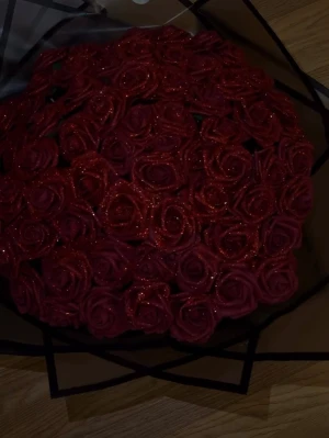 Bukett med röda glittriga rosor 100st - Stor bukett med konstgjorda röda rosor täckta av glitter, inslagna i svart dekorativt papper. Perfekt som present eller dekoration. Rosorna har en djup röd färg och glittrande yta som ger ett lyxigt intryck. 100 rosor. Pris går såklart att diskutera!
