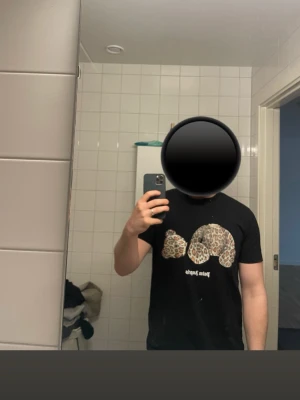 Svart t-shirt med leopardmönster - Svart t-shirt från Palm Angels med stort leopardmönstrat tryck framtill. Klassisk passform och rund halsringning. Perfekt för dig som vill sticka ut med en cool och trendig look.