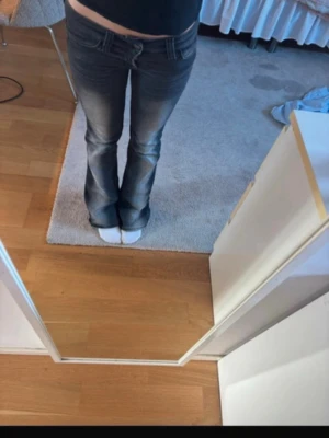 Bootcut jeans med låg midja - Säljer ett par mörkblå bootcut jeans med låg midja och slitningar framtill. Jeansen har klassisk femficksdesign och är tillverkade i denim med stretch för skön passform. Perfekta för en avslappnad och trendig look.