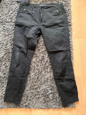 Svarta jeans - Säljer ett par svarta jeans med smal passform och dragkedjor vid fickorna. Klassisk femficksmodell och stretchigt material som sitter snyggt. Perfekta till en avslappnad eller trendig look.