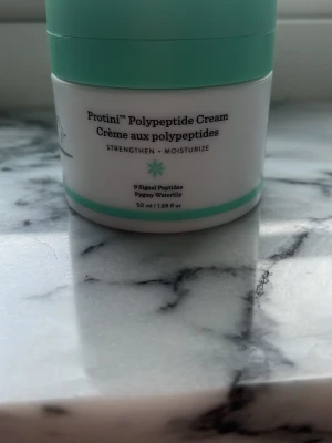 Drunk Elephant Protini Polypeptide Cream - Protini Polypeptide Cream från Drunk Elephant är en ansiktskräm med 8 signalpeptider och pygmévattenlilja. Burken är vit med mintgrönt lock och rymmer 50 ml. Krämen stärker och återfuktar huden och har en modern, stilren design. Original priset är 839kr, jag har andvänt den 2/3 gånger 