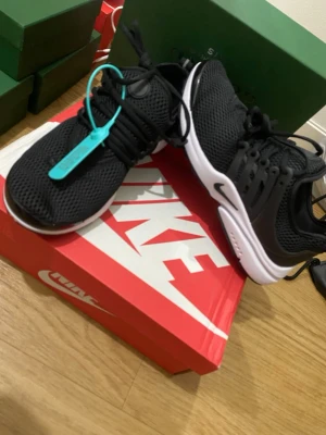 Nike Air Presto (helt nya) - Nike Air Presto sneakers i svart mesh med vita sulor och svarta detaljer. Skorna har en sportig design med plastdetaljer på sidorna och en turkos tag på snörningen. Perfekta för dig som gillar stilrena och bekväma sneakers.
