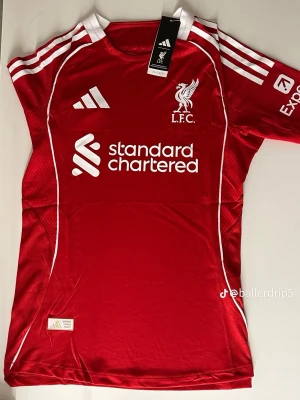 Liverpool matchtröja röd Adidas - Stilren och högkvalitativ fotbollströja inspirerad av Liverpools klassiska design. Tröjan är tillverkad i ett bekvämt och ventilerande material som passar både för träning och vardagsbruk. Storlekar: S, M, L Skick: Ny