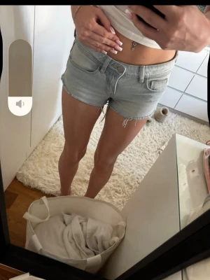 Ljusblå denimshorts med fransig kant - Snygga ljusblå denimshorts med fransig kant och slitningar baktill. Klassisk femficksmodell med knapp och dragkedja framtill. Perfekta för varma dagar och enkel att matcha med crop tops eller linnen.