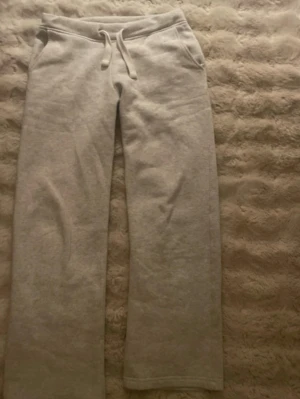 Ljusgrå mjukisbyxor från Russemerch  - ljusgrå mjukisbyxor från Russemerch med raka ben. Byxorna har två sidofickor och är tillverkade i mjukt sweatshirtmaterial, perfekta för chill dagar hemma eller när du vill vara bekväm.