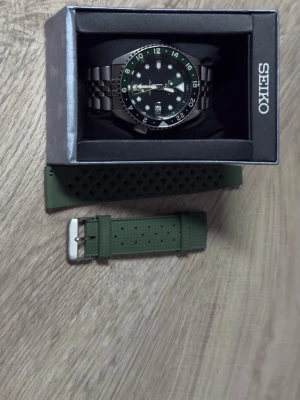 Seiko 5 GMT Grön urtavla med extra strap. - Seiko 5 GMT “Green Dial” – Automatisk (2025) – Fullset + Extra Strap  Säljer min Seiko 5 GMT SSK035K1 med grön tavla. Köpt 2025, i bra skick och fungerar felfritt.  Skick: • Mindre ytliga repor • Håller tiden bra  Specifikationer: • Automatisk • GMT-funktion • Datumvisning • Jubilee-länk  Ingår: • Box & papper (fullset) • Extra länkbitar • Extra grön gummirem  ✨ Sportig och stilren klocka som passar till allt – perfekt även för resor tack vare GMT.  📩 Hör av dig vid frågor eller fler bilder