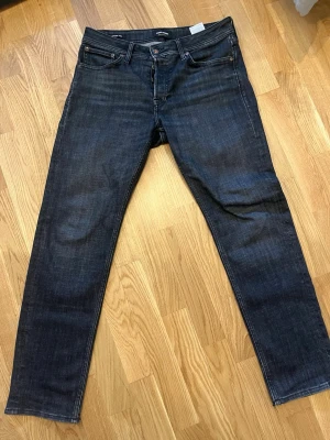Mörkblå tapered jeans Tapered/Mike jack&jones  - Säljer ett par mörkblå jeans i modellen Tapered/Mike. Jeansen har klassisk femficksdesign, normal midja och avsmalnande ben. Materialet är denim med snygg tvätt och subtila slitningar. Perfekta för en avslappnad men ändå stilren look.