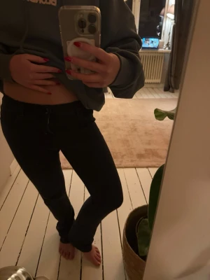 Svarta raka jeans - Säljer ett par svarta jeans med rak passform men även utsvängda nere och normal midja. Jeansen har klassisk femficksdesign och stängs med dragkedja och knapp. (Material=mjukare jeans).