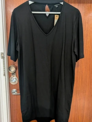 Svart v-ringad klänning River Island - En svart klänning från River Island med v-ringning och korta ärmar. Klänningen har en rak passform.