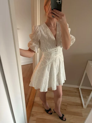 Adoore Sicily Dress - storlek 36 - Säljer min vita, feminina klänning med v-ringning, puffärmar och markerad midja. Smickrande passform och vackert broderat tyg. Perfekt till student, sommarfest, bröllop eller semester 🌿   Endast använd en gång på studenten – i toppskick ✨  🚭 Rök- och djurfritt hem 📦 Snabb frakt  Pris kan diskuteras❗️
