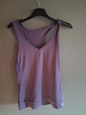 Ljuslila ärmlös träningströja💕 - Säljer en enkel och snygg ljuslila linnetopp med v-ringning. Toppen är ärmlös och har en klassisk, rak passform som passar perfekt till jeans eller kjol. Materialet känns mjukt och skönt💕