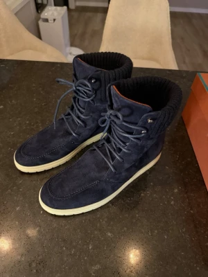 Loro piana Ontario walk - Snygga mörkblå kängor i mocka med vita sulor och högt skaft. Kängorna har snörning framtill och ribbstickad mudd upptill för extra komfort och stil. Perfekta för dig som vill ha en modern och avslappnad look.