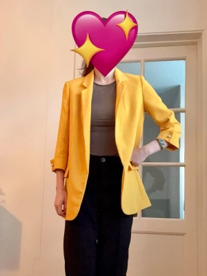 Gul oversized kavaj blazer med slag och pärldetaljer på ärmarna - Snygg gul kavaj i med klassiska slag och trekvartsärmar. Kavajen har dekorativa ficklock och pärlor vid ärmsluten. Perfekt för dig som vill sticka ut med färg eller som vill ha en kavaj som är perfekt nu till våren. Bekväm och har en glansig insida. Från Zara. Fint skick. Materiallappen är tyvärr bortklippt.