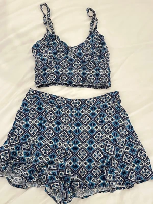 Blått mönstrat set  - Säljer ett tvådelat set från Hollister med crop top och shorts i blått och vitt geometriskt mönster. Toppen har smala axelband och shortsen är lösa och bekväma🫶🏼s-m