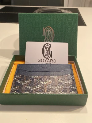 Blått kortfodral  - Snyggt blått kortfodral med ett snyggt mönster i blå, vit och brunt. Tillverkat i läder och är perfekt för att hålla koll på dina kort. Kommer i en ask med en logga på och ett exklusivt kort. En stilren accessoar för dig som gillar lyxiga detaljer. Är i perfekt skick och har aldrig använts. Hör av dig för frågor!